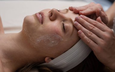 Kaplıca salonundaki güzel kadın. Yüz masajı tedavisi. Kız yüz tedavisi. Cilt bakımı. Yüz kilinden maske takan spa kadını, yakın plan. Güzellik kliniğinde cilt masajı. SPA 'da yüz gerdirme.