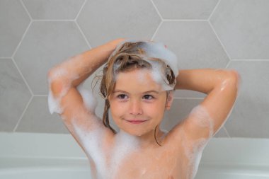 Küvette köpükle yıkanan şirin bir çocuk. Banyoda banyo yapan komik çocuk suratı. Sabun köpüklü banyo küveti
