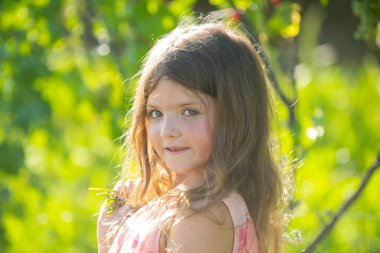 Bahar çocuğu suratı. Bahar çiçekli küçük sarışın bir kızın portresi. Arka bahçedeki komik çocuklar. Çocuklar çiçek arkaplanda yüzlerini kapatırlar. Çocuklar bahar çiçeklerinde oynar.