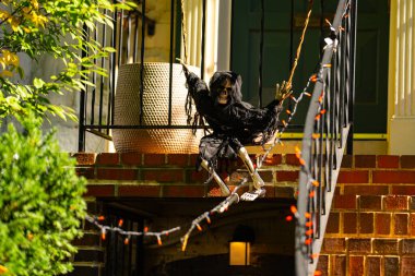 Cadılar Bayramı süslemeleri. Cadılar Bayramı balkabağı ve dekore edilmiş ev için iskelet. Bir Amerikan evinin ön bahçesinde dekore edilmiş korkunç bir şey. Şeker mi şaka mı? Cadılar Bayramı geçmişi. Cadılar Bayramı 'nın sonbahar tatili