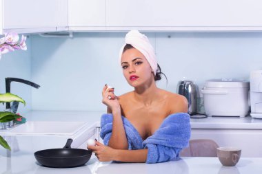 Çekici bir kadın mutfakta seksi poz veriyor. Çekici, şehvetli, çıplak kadın ev hanımı. Mutfakta yemek pişiren çekici bir kız. Mutfakta zayıf vücutlu bir kadın. Seksi kadın mutfakta yemek hazırlıyor.