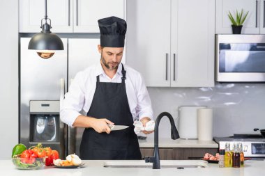 Aşçı mutfakta sebzelerle yemek pişiriyor. Sağlıklı yemek. Mutfakta yemek pişiren çekici beyaz adam. Modern mutfakta sağlıklı yemek pişiren adam. Şef mutfakta yemek hazırlıyor.