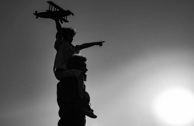Baba 'nın gün batımında oğlunun omuzlarında taşıdığı siluet. Çocuk ve baba oynuyor. Çocuk pilot ve baba seyahat etmeyi hayal ediyor.