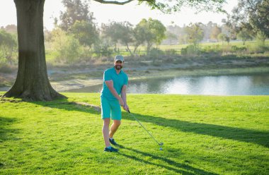 Profesyonel golf sahasında erkek golfçü. Golf sopalı bir golfçü ateş ediyor.