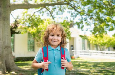 Back to school. Pupil of primary school on the way to study. Beginning of lessons. Boy outdoors near school park clipart