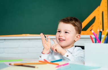 Sınıfın içinde arka planda tahtası olan mutlu çocuk. Okula geri dön.