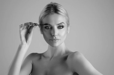 Koyu kaşlı güzel bir kadın kaş fırçası tutuyor. Kaş kaplaması. Güzellik prosedürlerini uygula. Kaş ve kaş çizgisi, kaş çizgisi.