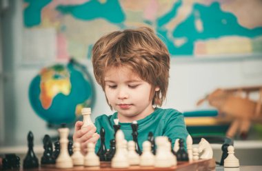 Anaokulu ya da okul çocuğu, düşünen çocuk. Çocuk odada satranç oynuyor. Satrançlı küçük çocuk