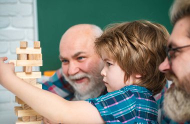 Büyükbabam torununa Jenga oynamayı öğretiyor. Büyükbaba ve oğul birlikte eğleniyorlar. Erkek Aile Jenga Oynuyor