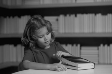 Eğitim Konsepti. Öğrenci çocuk kütüphanede kitap okuyor. Çocuklar okumayı öğrenir. Öğrenci kütüphanede kitap okuyor. Ödev yapan okul çocuğu, sınıfta sıkı çalış.