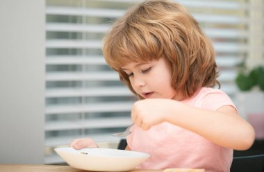 Bir tabak çorbası olan komik bir çocuk. Çocuk yemeği.