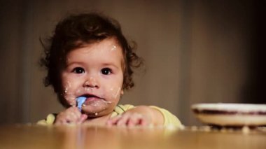 Sevimli bir bebek kaşıkla yemek yer. Çocuk maması yiyen aç küçük bir çocuk. Bebek yulaf lapası. Yemek zamanı. Küçük bebek sağlıklı yiyecekler yiyor. Küçük bir bebek yemeğini yiyor. Yiyeceği olan çocuğun yakın plan portresi