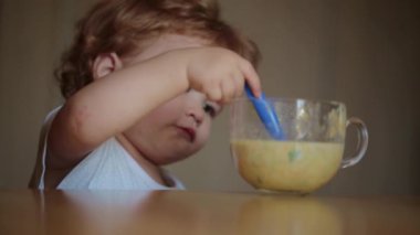 Bebek kaşıkla çorba içiyor. Çocuk yemeğini ye. Çocuk maması yiyen aç küçük bir çocuk. Bebek yulaf lapası. Küçük bebek sağlıklı yiyecekler yiyor. Küçük bir bebek yemeğini yiyor. Yiyeceği olan çocuğun yakın plan portresi