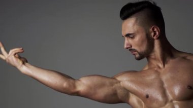 Kaslı seksi adam kaslarını esnetiyor. Erkek sporcu, kaslarını esneten sporcu, kas kaslarına bakıyor. Erkek kas pazısı kolu. El, kol bisepsi, yakın plan. Güçlü, seksi ve üstsüz erkek model.