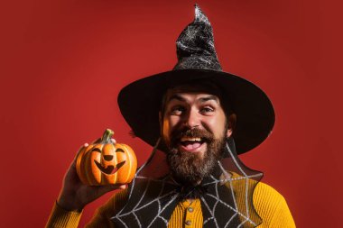 Cadılar Bayramı balkabaklı komik bir model. Cadılar Bayramı şapkalı balkabaklı insan portresi. Şeker mi şaka mı? Cadılar Bayramı şapkalı korkunç hippi. Cadı şapkalı adam balkabağını tutuyor. Komik Cadılar Bayramı