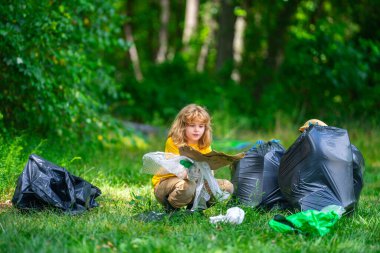 Küresel çevre kirliliği. Çocuk dışarıda plastik çöp topluyor. Çevre koruma kavramı. Çocuk çöp torbasına atık koyuyor. Eko çocuklar gönüllü. Çevre kirliliği