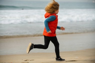 Mutlu çocuk denize koşuyor. Çocuk sahilde eğleniyor, deniz havuzu işletiyor. Doğada koşan koşucu çocuk. Aktif sağlıklı çocuk yaşam tarzı