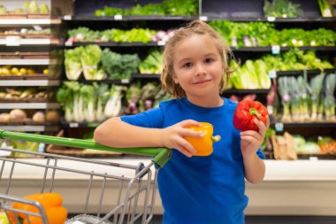 Markette sebze ve biberli çocuk. Süpermarkette alışveriş yapan bir çocuk. Markette, ürünleri seçerken. Sağlıklı alışveriş.