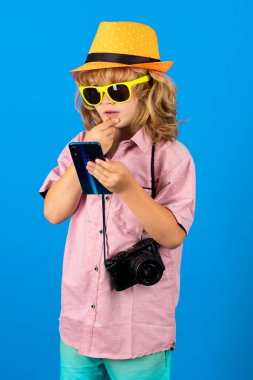Çocuk turist. Sevimli çocuk fotoğraf makinesi ve telefonla fotoğraf çekiyor. Gezgin çocuk telefonda sohbet ediyor. Tatil seyahat yaşam tarzı