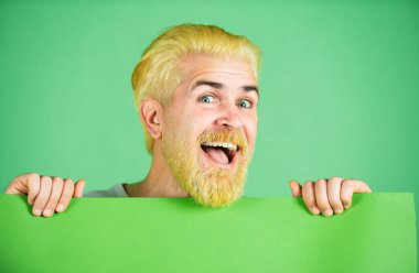 Kızıl saçlı komik adam elinde bayrak tutuyor. Metin ya da slogan ekle. Moda konsepti stüdyosunda poz veren beyaz sarışın erkek manken.