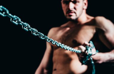 Siyah arka planda zincirli kaslı bir adam.