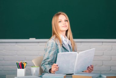 Elinde kitap tutan genç bir üniversite öğrencisinin portresi. Sınıfta karatahta geçmişi olan bir öğrenci.