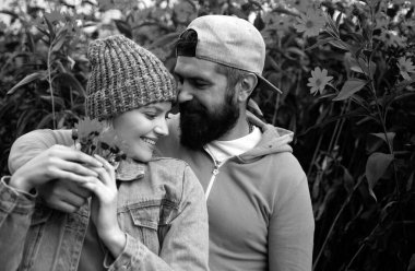 Genç aşık çift, sonbahar parkında birbirlerine çiçeklerle sarılıyorlar. Aşk hikayesi.