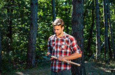 Oduncu elinde baltayla orman arka planında duruyor. Ormanların tahrip edilmesi doğal ekosistemlerin bozulması ve istikrarsızlaşmasının başlıca nedenlerinden biridir.