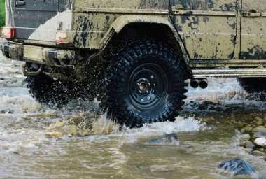 Dağ yolunda off-road yolculuğu. Alt manzaradan büyük off-road araba tekerine, şehir yolu ve dağ zemininde. Büyük 4x4 arabalı seyahat kavramı
