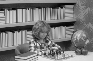 Child play chess in classroom at school. Chess for intelligent kid. Child genius, smart pupil playing logic board game