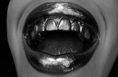 Altın dudaklar. Ağızdan gelen altın boya. Makyajlı kadın ağzında altın dudaklar.