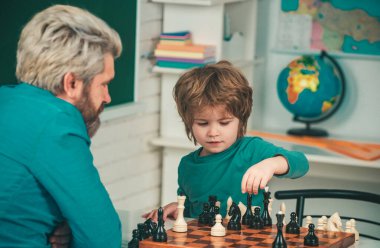 Satranç stratejisi geliştiren konsantre bir çocuk. Satranç stratejisi geliştiren sevimli çocuk. Yakışıklı öğretmen anaokulu çocuğuna özel ders veriyor.