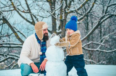 Mutlu Noeller ve Mutlu Yıllar. Mutlu baba ve oğul karda kardan adam yapıyor. El yapımı komik kar adam. Aile tatili ve birliktelik. Kar Bahçe'de baba ve çocuğun kış portresi