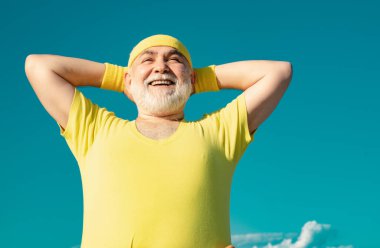 Özgürlük emekliliği kavramı. Mavi gökyüzü arka planında spor yapan yaşlı bir adam. Sağlıklı ve spor. Sağlık hizmetleri neşeli yaşam tarzı