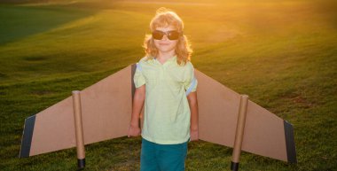 Çocuk gün batımında oyuncak uçak kanatlarıyla oynuyor. Bir pilot olmayı hayal et. Süper kahraman uçuyor.