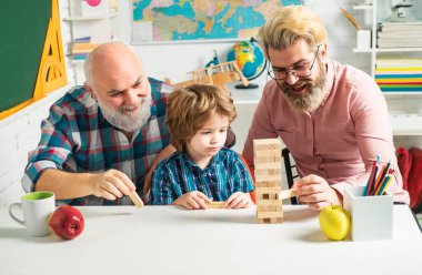 Three different generations ages: grandfather father and child son together. Happy man family have fun together. Grangfather, Father and son playing game at home clipart