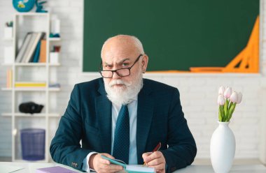 Profesör elinde bir kitap tutuyor ve beyaz arka planda izole edilmiş tahta bir sopayla işaret ediyor. Bilgi ve geleneksel eğitim kavramı