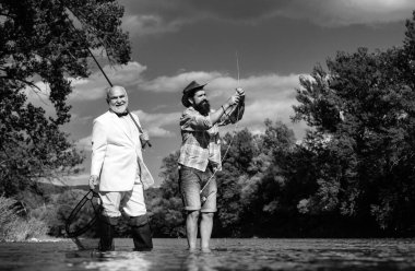 Takım elbiseli kıdemli balıkçı ve balıkçı oltasıyla balıkçılık yapan sıradan bir adam.