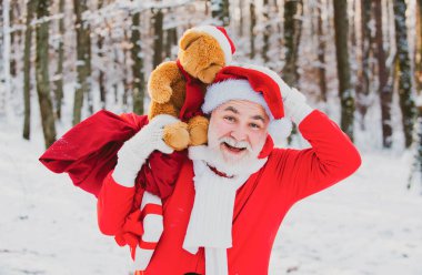 Noel Baba kış ormanına kar manzarasında hediye dolu bir çantayla geliyor. Noel Baba kış tarlasında. Noel Baba çocuklara hediye getirir.