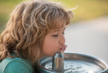 Dışarıdaki çeşmeden su içen çocuk. Susamış çocuk