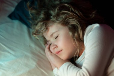 Tatlı uykular. Çocuk evde yatakta uyuyor. Yatma zamanı, çocuklar uyuyor. Çocuk yastıkta uyuyor, sağlıklı bir uyku çekiyor.