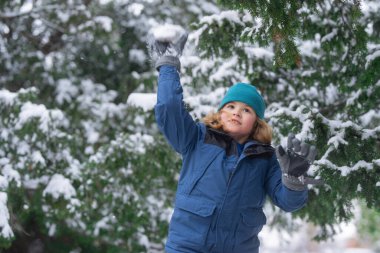Kartopu savaşı yapan bir çocuk. Kış tatili çocukları kar aktivitesi. Çocuk Noel tatilinin tadını çıkar. Karlı ormanda kışlık elbiseli bir çocuk. Beyaz karla kaplı ağaçlar. Çocuk kartopu oynarken iyi eğlenceler.