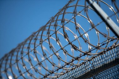 Çitteki dikenli teller. Güvenli bölgenin sınırlarını sınırlayan dikenli teller. Güvenlik, koruma ve sınırlar. Dikenli tel kirpi ve elektrikli çit. Bölge koruma kablosu