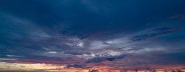 Gündoğumu arka planı. Dramatik görkemli gün batımı. Gökyüzü bulutlu ve arka planda gökyüzü aydınlığı var. Farklı şekillerde bulutlarla gün doğumu. Sakin gündoğumu gökyüzü ve bulutlar arasından güneş.