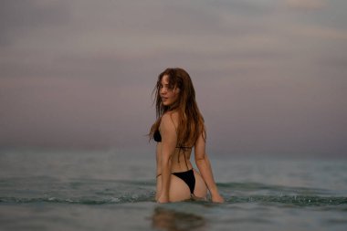 Plaj bikini vücudu hazır. Seksi, ince vücut. Güneş yanığı kadın. Suda bikinili bir kadın. Denizde bikinili genç bir kadın. Deniz kıyısındaki seksi moda kadını. Güzel kız kumsalda güneşleniyor.