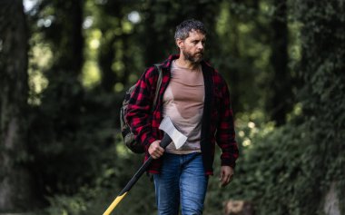 Kareli gömlekli yakışıklı ya da oduncu balta tutuyor. Oduncu ya da oduncu. Erkeklik kavramı. Vahşi, güçlü, çekici bir adam ormanda baltayla odun kesiyor. Ormanda baltası olan oduncu.