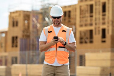 Erkek inşaat mühendisi. İnşaat alanında mimar. Çalışanlar telefon kullanıyor, inşaatçılar işten sonra telefonda sohbet ediyor. Cep telefonu olan bir mimar. İnşaat yöneticisi