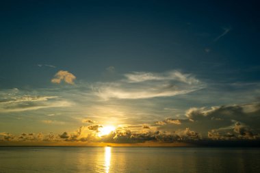 Gündoğumu denizi. Bulutların arasından gün batımını izleyen sakin bir deniz. Meditasyon okyanusu ve gökyüzü arka planı. Huzurlu deniz manzarası. Günbatımı deniz suyunun üzerinde bir ufuk. Gün batımı gökyüzü sakin
