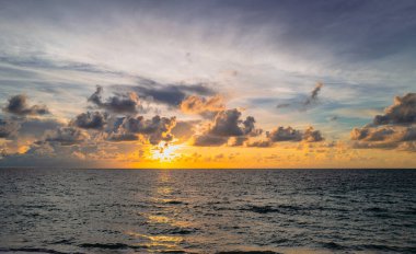 Deniz batımında bulutlu gökyüzü, okyanus sahilinde gün doğumu. Gün batımından sonra gökyüzünde gün batımı manzarası. Gökyüzüne ve denize karşı farklı renkte bulutlarla gün doğumu