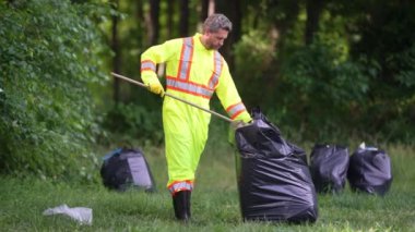 Dışarıdaki çöpleri toplayan gönüllü adam. Ekoloji konsepti. Çevre kirliliği. Dünya Günü. Çöp tenekelerini geri dönüşümle temizleyin. Doğa temizliği. Çevre plastik kirliliği